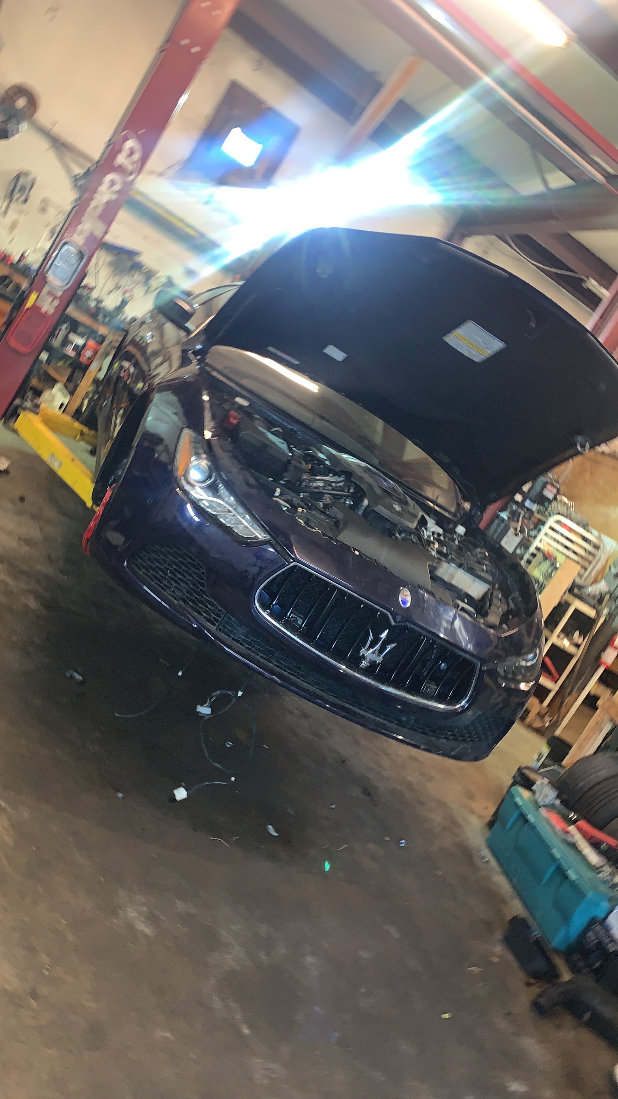 A car up on the lift in our shop with the engine bay open